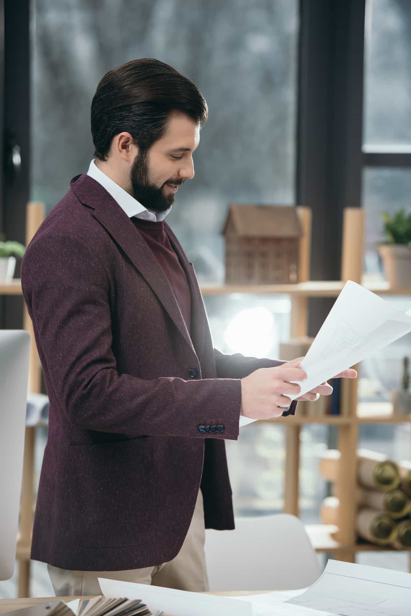 handsome architect working with blueprints in modern office